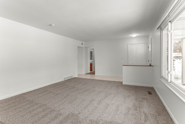 unfurnished room featuring light carpet, visible vents, and baseboards