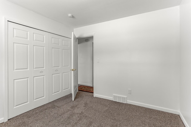 unfurnished bedroom featuring carpet floors, baseboards, visible vents, and a closet