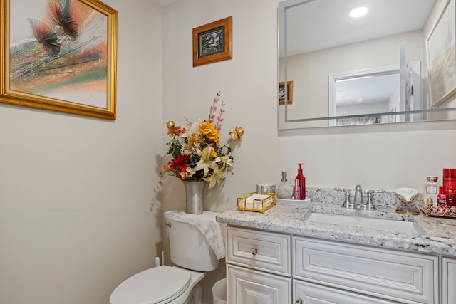 half bath featuring recessed lighting, vanity, and toilet