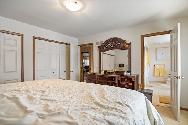 bedroom with light carpet, visible vents, baseboards, multiple closets, and ensuite bath