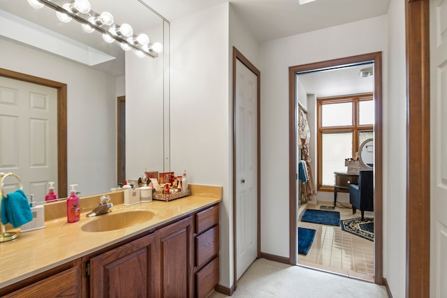 bathroom featuring a closet, vanity, and baseboards