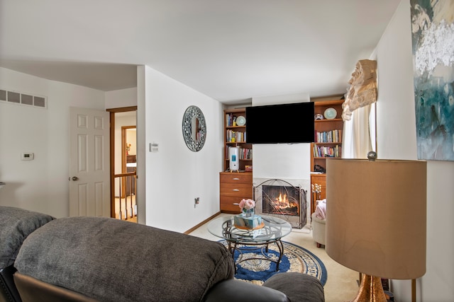 living room featuring baseboards, a lit fireplace, visible vents, and light colored carpet