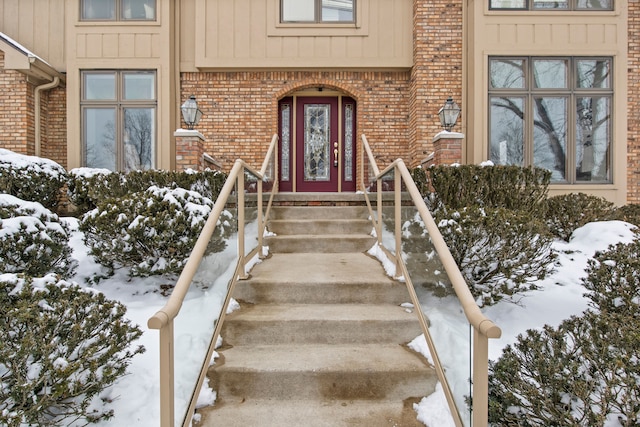 snow covered property entrance with brick siding