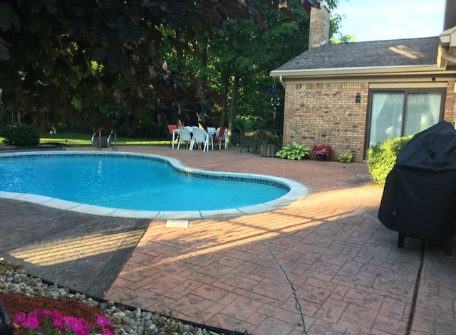 outdoor pool featuring grilling area and a patio