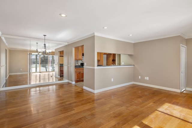 spare room with recessed lighting, ornamental molding, a chandelier, light wood-type flooring, and baseboards