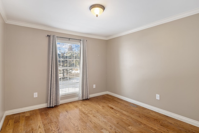 unfurnished room with ornamental molding, light wood-style flooring, and baseboards