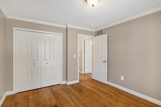 unfurnished bedroom with a closet, visible vents, baseboards, and wood finished floors