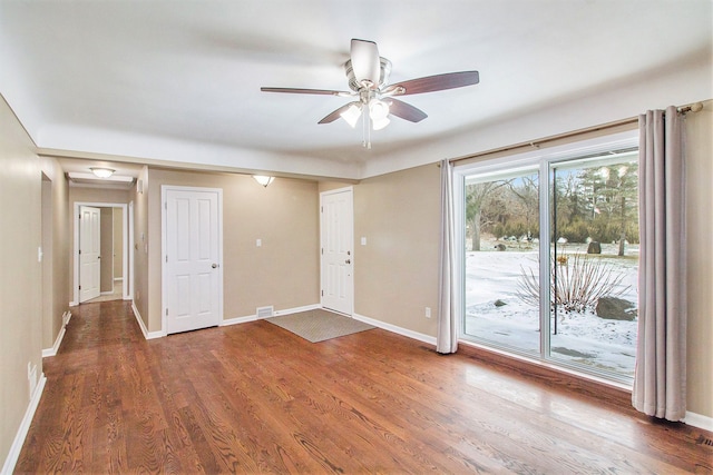 interior space with ceiling fan, wood finished floors, visible vents, and baseboards