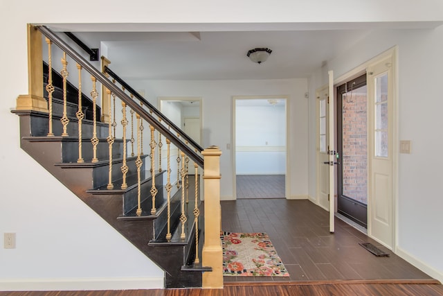 entryway with stairway, visible vents, baseboards, and dark wood-type flooring