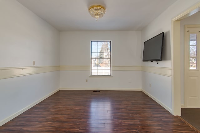 empty room with a healthy amount of sunlight, baseboards, and dark wood-style flooring