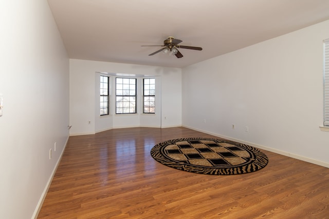 unfurnished room featuring ceiling fan, wood finished floors, and baseboards