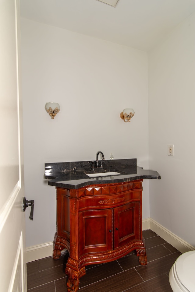 bathroom with wood tiled floor, toilet, vanity, and baseboards