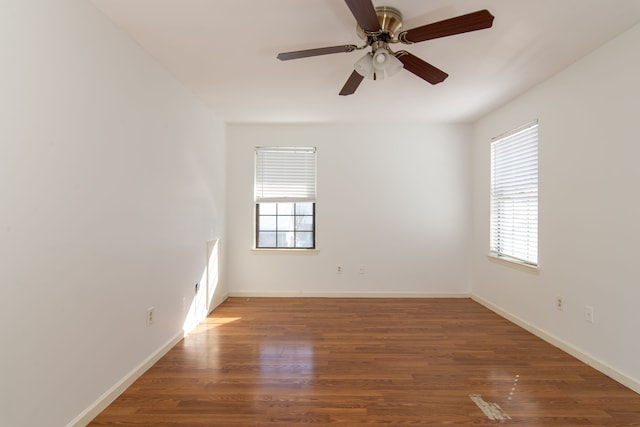 empty room featuring dark wood-style floors, plenty of natural light, baseboards, and a ceiling fan