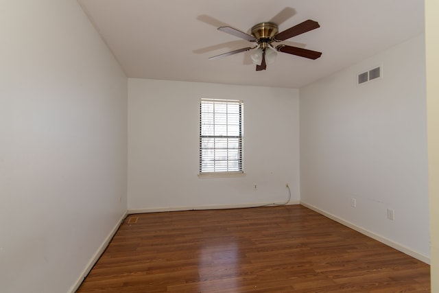 spare room featuring dark wood-style floors, baseboards, visible vents, and a ceiling fan