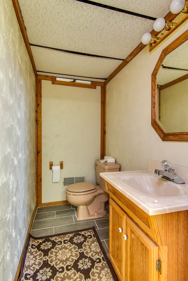 half bath featuring toilet, visible vents, and vanity