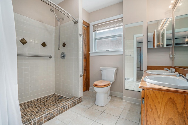 bathroom featuring vanity, a tile shower, tile patterned floors, and toilet