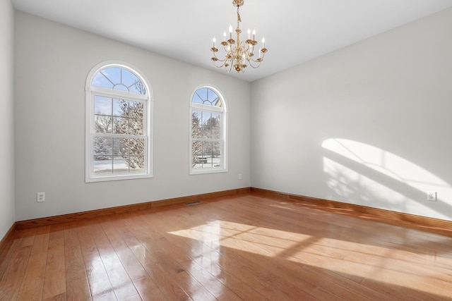 empty room featuring an inviting chandelier and light hardwood / wood-style flooring