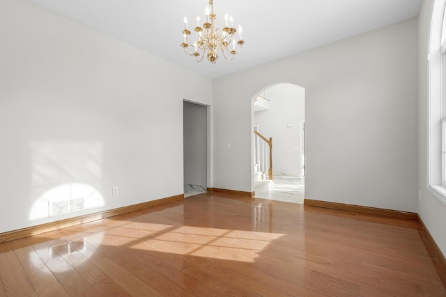 spare room with hardwood / wood-style flooring and an inviting chandelier