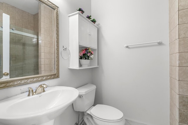 bathroom featuring toilet, a shower with door, and sink