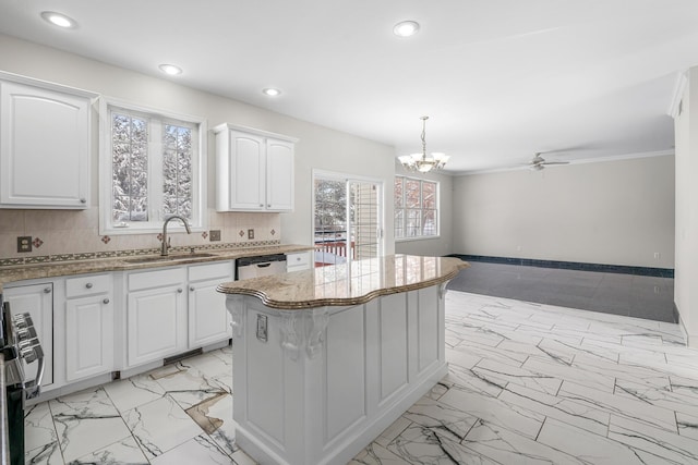 kitchen with sink, appliances with stainless steel finishes, white cabinetry, hanging light fixtures, and a kitchen island