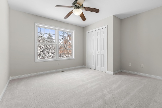 unfurnished bedroom featuring light colored carpet, ceiling fan, and a closet