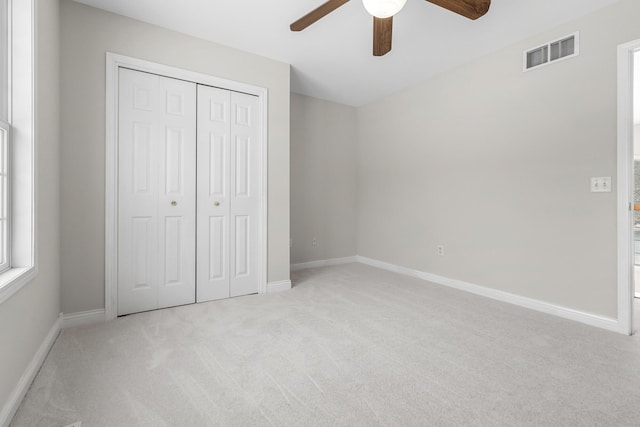 unfurnished bedroom with ceiling fan, a closet, and light carpet