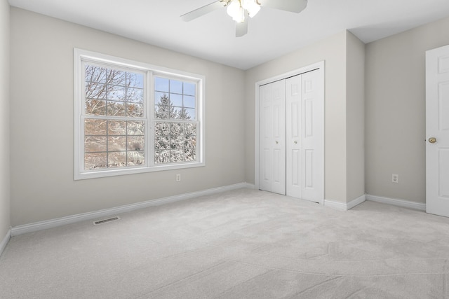 unfurnished bedroom featuring ceiling fan, a closet, light carpet, and multiple windows