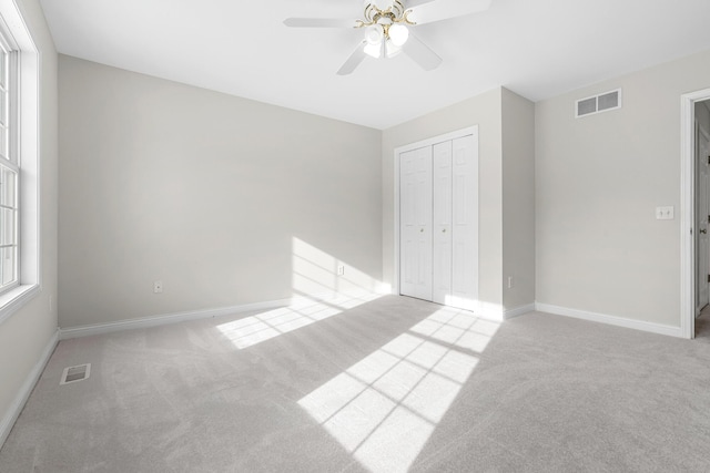 unfurnished bedroom with light carpet, ceiling fan, and a closet