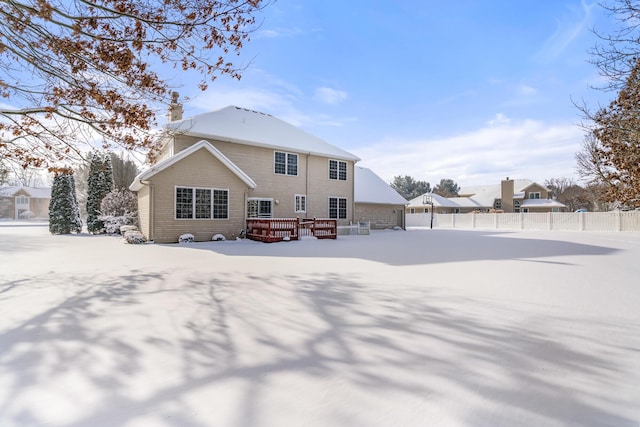 snow covered rear of property with a deck