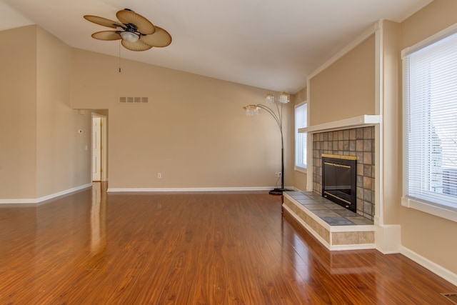 unfurnished living room featuring baseboards, visible vents, lofted ceiling, wood finished floors, and a fireplace