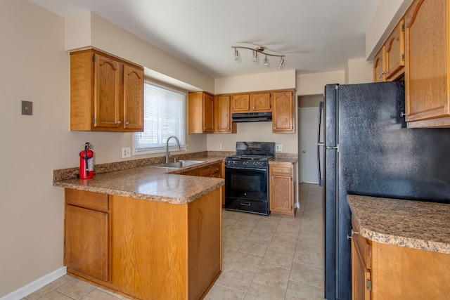 kitchen with brown cabinets, light tile patterned floors, a sink, under cabinet range hood, and black appliances