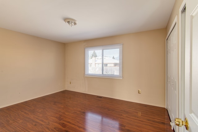 unfurnished bedroom featuring a closet, baseboards, and dark wood-type flooring