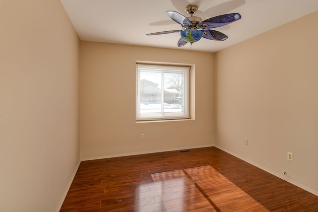 spare room featuring a ceiling fan, baseboards, and dark wood-style flooring