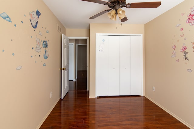 unfurnished bedroom with dark wood-style floors, a closet, visible vents, ceiling fan, and baseboards