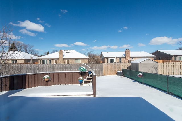 yard layered in snow featuring a shed, an outdoor structure, and a fenced backyard