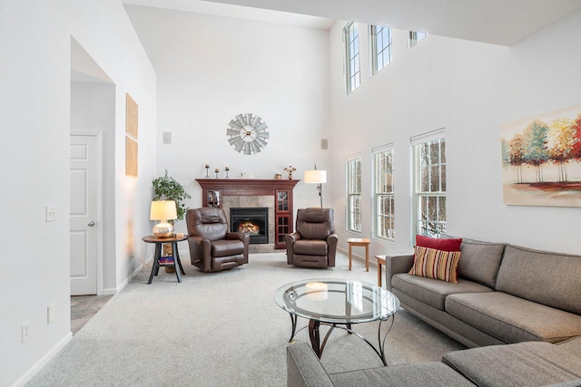 carpeted living room with a towering ceiling, a healthy amount of sunlight, and a tiled fireplace