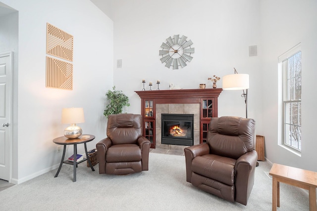 living area featuring light colored carpet, a tile fireplace, and a high ceiling