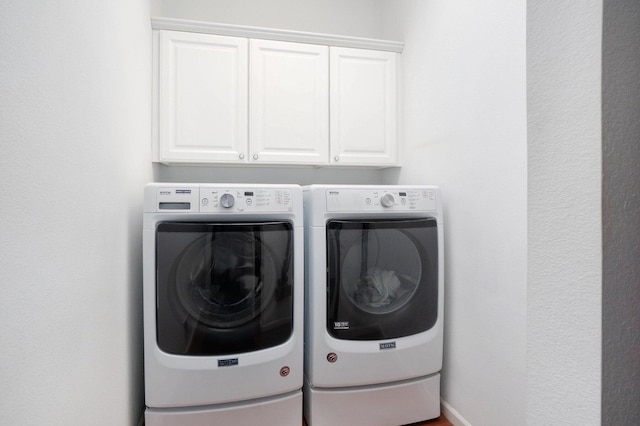 clothes washing area featuring cabinets and washing machine and dryer