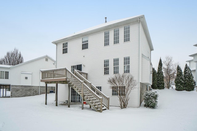 snow covered rear of property with a deck