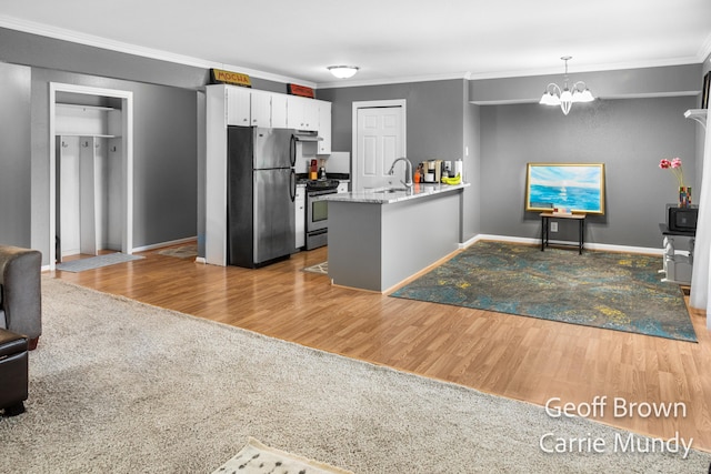 kitchen featuring a chandelier, ornamental molding, appliances with stainless steel finishes, kitchen peninsula, and white cabinets