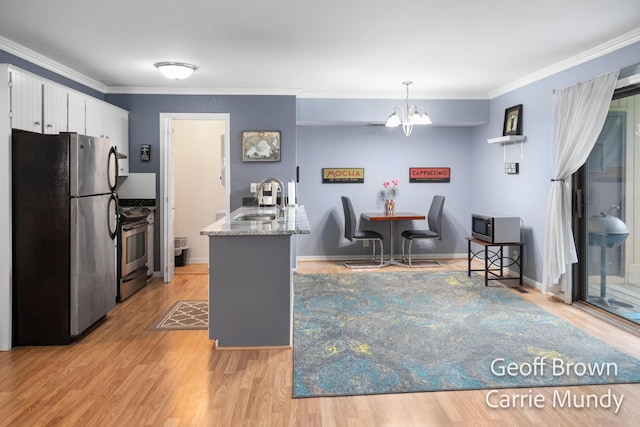 kitchen with sink, appliances with stainless steel finishes, a kitchen island with sink, white cabinets, and decorative light fixtures