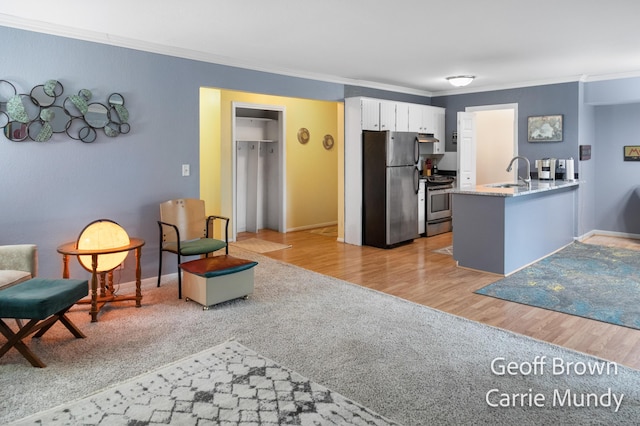 kitchen with sink, white cabinetry, ornamental molding, appliances with stainless steel finishes, and kitchen peninsula