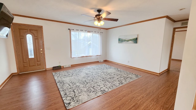 foyer entrance with visible vents, baseboards, wood finished floors, and ornamental molding