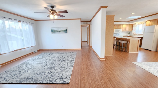 unfurnished living room featuring light wood-style flooring, ceiling fan, baseboards, and ornamental molding