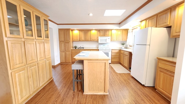 kitchen featuring a breakfast bar, white appliances, light wood-style flooring, and light countertops