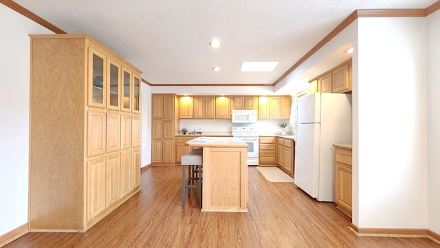 kitchen with a kitchen bar, ornamental molding, light wood-style flooring, white appliances, and light countertops