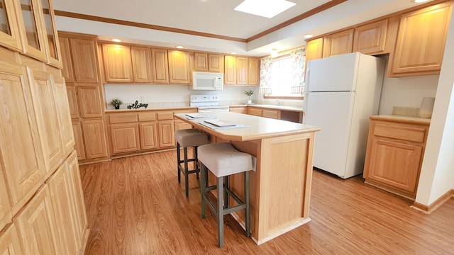 kitchen featuring light wood finished floors, a kitchen breakfast bar, a center island, white appliances, and light countertops