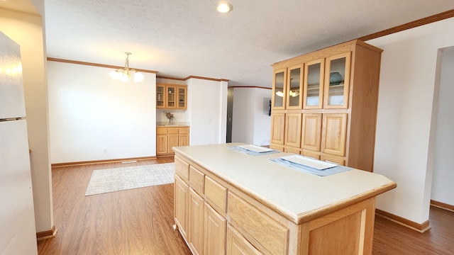 kitchen with baseboards, a center island, wood finished floors, and crown molding