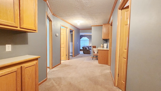 hall with light colored carpet, a textured ceiling, crown molding, and baseboards