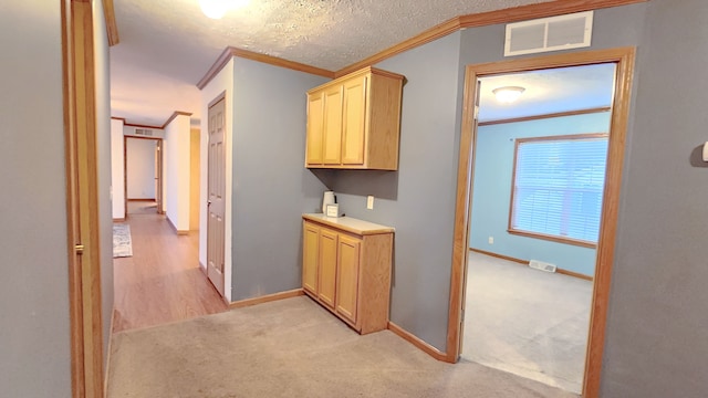 hall featuring crown molding, baseboards, visible vents, and light carpet